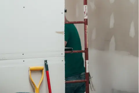 Prace remontowe w toku. Zastanawiasz się, ile schnie gips szybkoschnący? Na budowie widać rusztowanie i narzędzia.