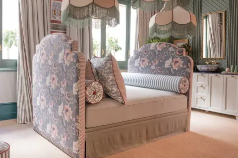 Un cabecero tapizado con flores rosas y azules, bordes a rayas y cojines a juego. Inspiración para como tapizar un cabecero.