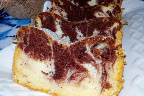 Wilgotne ciasto z białek w paski czekoladowo-waniliowe, posypane cukrem pudrem, prezentuje się apetycznie.