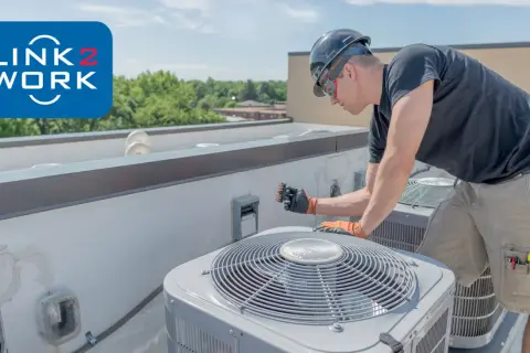 Doświadczony monter wentylacji pracuje na dachu, naprawiając jednostkę klimatyzacyjną.