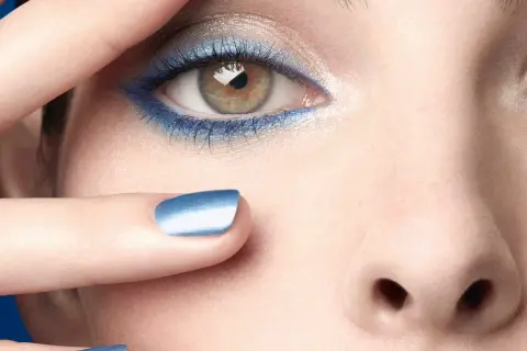 Occhi con ombretto blu elettrico e unghie abbinate, un tocco di **chanel cipria** per un look audace.
