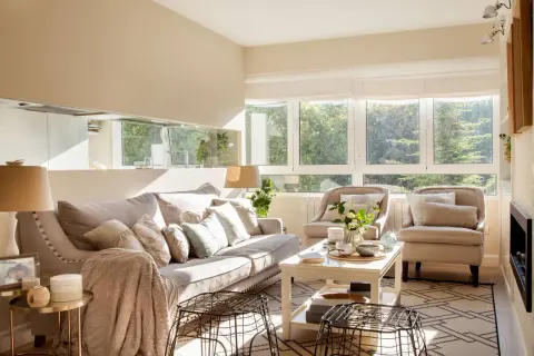 Salón luminoso con sofá y sillones en tonos neutros. La paleta de colores para pintar salones es cálida y acogedora, inspirada en la luz natural.