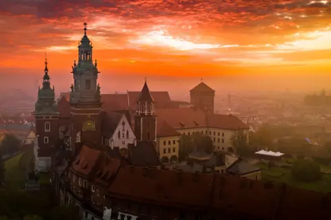 Wawel o wschodzie słońca, z ognistym niebem i mgłą unoszącą się nad miastem. Czuć energię czakramu wawelskiego.