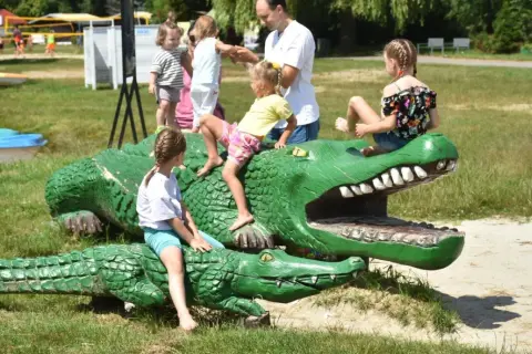 Dzieci bawią się na drewnianych krokodylach, które są jednymi z atrakcji dla dzieci w Okunince.