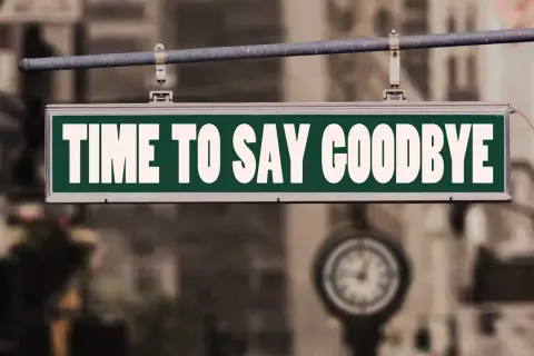 Ein Schild mit der Aufschrift "TIME TO SAY GOODBYE" hängt über einer Straße. Es ist Zeit für einen **Lied Abschied**.