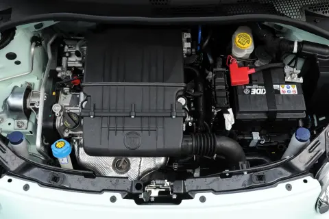 Silnik w fiat 500 l. Widoczny akumulator, osłona silnika z logo FIAT, zbiorniczki płynów i elementy układu dolotowego.