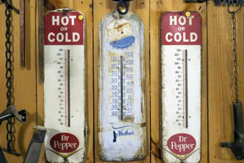 Trzy stare termometry wiszą na drewnianej ścianie. Dwa z nich reklamują Dr Pepper, jeden pokazuje "Ay Weather's". Idealne do monitorowania temperatury w biurze.