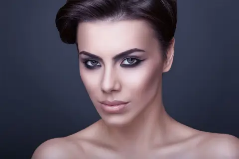 Volto di donna con trucco drammatico, labbra carnose e occhi all'ingiù che catturano lo sguardo.