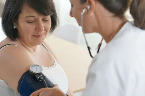 Lekarka bada ciśnienie pacjentce za pomocą ciśnieniomierza. To ważny element profilaktyki, który pomaga monitorować stan zdrowia i wykrywać ewentualne problemy, np. z układem krążenia.