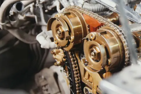 Mechanizm rozrządu DOHC z widocznym łańcuchem, a nie paskiem. Złote koła zębate i metalowy łańcuch.
