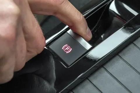 Palec naciska przycisk z symbolem hamulca ręcznego. Tak odblokujesz hamulec ręczny elektryczny.