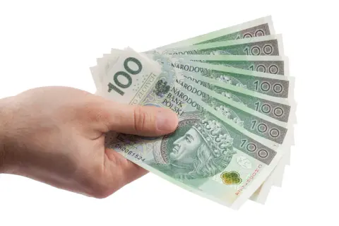 Dłoń trzyma wachlarz banknotów 100 zł. Może to być zapłata za zachowek lub po prostu wypłata pieniędzy.