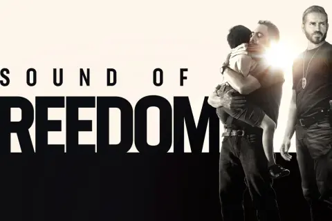 Sound of Freedom" Stream: Ein Mann umarmt ein Kind, während ein Polizist daneben steht.