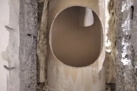 Otwór w ceramicznym kominie, przygotowany do dalszych prac. Widać izolację i fragmenty konstrukcji.