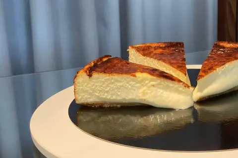 Trois parts de cheesecake basque, avec leur croûte caramélisée et leur cœur crémeux, prêtes à être dégustées.