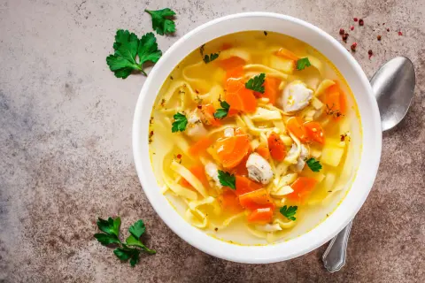 Aromaticzny rosół z indyka z makaronem i marchewką, udekorowany natką pietruszki. Idealny na chłodne dni.