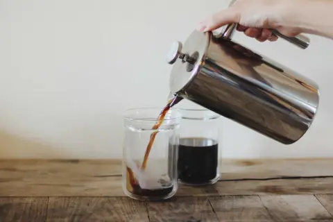 Versando caffè americano da una french press in due bicchieri. Le dosi caffè americano sono perfette per iniziare la giornata.