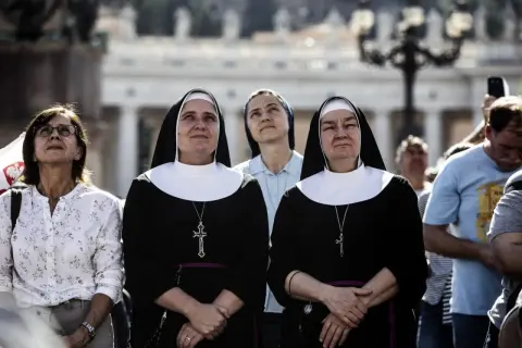 Dwie zakonnice w czarnych habitach z białymi kołnierzami patrzą w górę. Ich habit to symbol ich powołania.