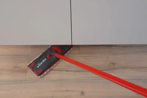 Mocio Vileda rosso pulisce il pavimento in legno, mostrando come smacchiare il legno con facilità.