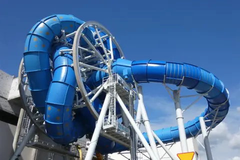 Aquapark Reda: niebieska zjeżdżalnia z rekinami, wirująca konstrukcja z rur, podniebna przygoda.