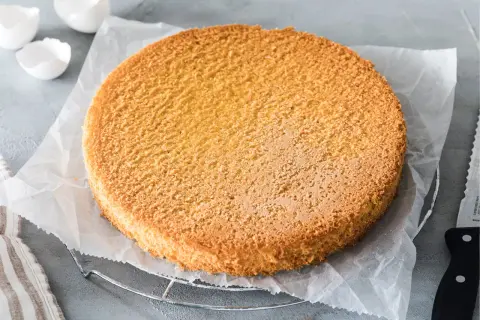 Ein goldbrauner, luftiger Tortenboden liegt auf Backpapier. Perfekt für jedes Tortenboden Rezept.