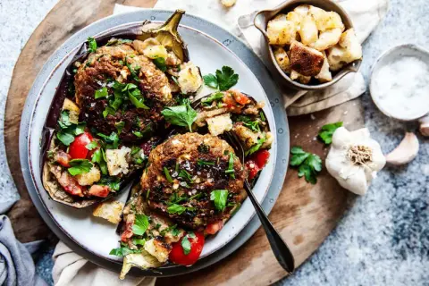 Ugnsbakad aubergine fylld med köttfärs, tomater och krutonger, toppad med färsk persilja. En härlig aubergine i ugn.