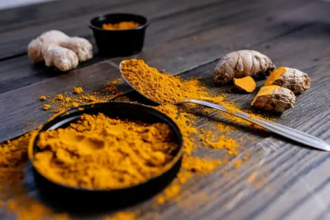 Poudre de curcuma et racines sur fond de bois. Le curcuma est connu pour ses nombreux cumin bienfaits.
