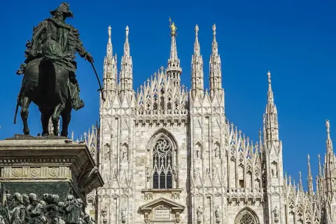 Statua equestre davanti al maestoso Duomo di Milano, con le sue guglie che svettano verso il cielo azzurro.