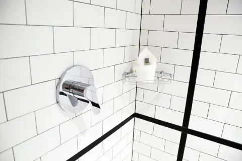 Coin de douche moderne avec robinetterie chromée et porte-savon. Idéal pour nettoyer la faience salle de bain.