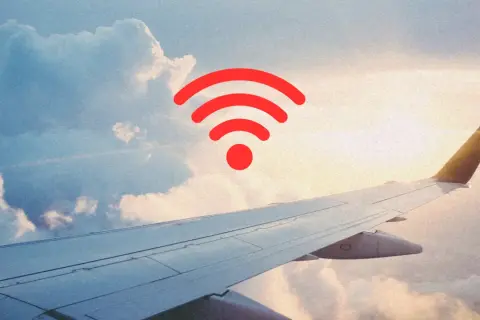 Widok z okna samolotu na chmury i skrzydło. Czerwony symbol Wi-Fi sugeruje, czy w samolocie jest wifi.