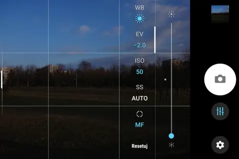 Aparat w telefonie z widokiem na park. Na ekranie opcje: WB, EV, ISO 50, SS AUTO, MF. Jak ustawić długi czas naświetlania w telefonie?