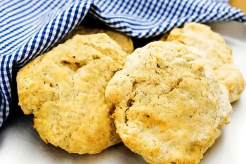 Nyttiga scones, gyllene och fluffiga, vilar under en blåvitrutig handduk. Perfekt för en hälsosam fika.