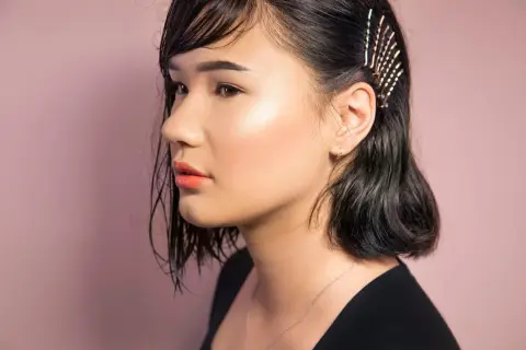 Ein Mädchen mit dunklen, nassen Haaren, die mit Glitzer-Haarnadeln geschmückt sind. So kann man seine **Haare richtig stylen** für einen besonderen Look.