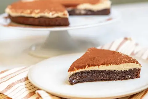 En saftig kladdkaka med en krämig topping, pudrad med kakao. Perfekt för fikat!