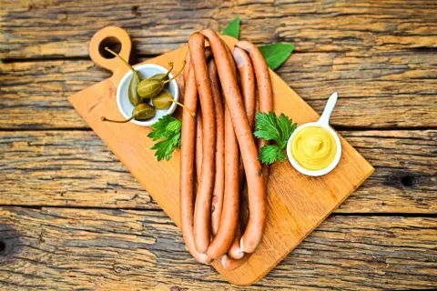 Parówki z szynki na desce z kaparami i musztardą. Idealne na grilla lub jako dodatek do dania.