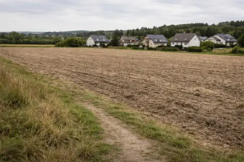 Pola uprawne obok domów, gotowe do przekształcenia. Zastanawiasz się, jak odrolnić działkę?