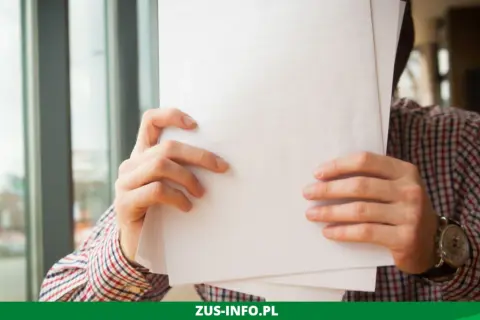 Mężczyzna w kratę trzyma dokumenty, być może wniosek o niezaleganie ZUS.