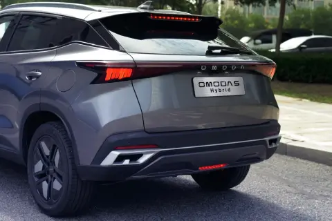 Szary OMODA 5 Hybrid z tyłu, z widocznym napisem "OMODA Hybrid" na klapie bagażnika. Nowoczesne światła LED i sportowy dyfuzor.