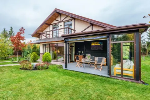 Porche acristalado con muebles de exterior, ideal para saber como cerrar un porche para el invierno y disfrutarlo todo el año.