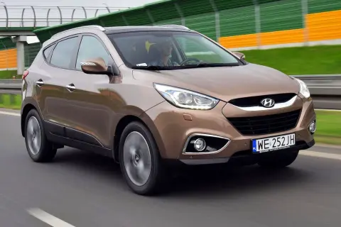Brązowy Hyundai ix35 w ruchu drogowym, z widocznym kierowcą.