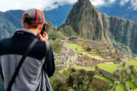 Turysta robi zdjęcie Machu Picchu. To idealne miejsce, by sprawdzić, kiedy najlepiej lecieć do Peru, by podziwiać te cuda.