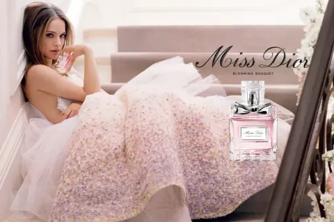 Kobieta w tiulowej sukni trzyma flakonik Miss Dior Blooming Bouquet.