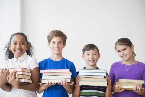 Vier lächelnde Kinder der 3. Klasse präsentieren stolz ihre Bücher für die buchvorstellung klasse 3.