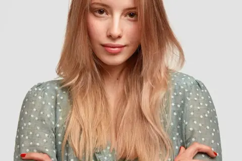 Mujer joven con peinados pelo liso, rubio y degradado, con un vestido verde de flores blancas.