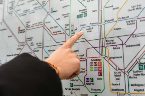 Palec wskazujący na mapę metra w Barcelonie, szukając trasy z lotniska.