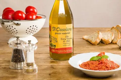 Un plat de pappa al pomodoro, garni de basilic, avec des tomates fraîches, du pain, de l'huile d'olive et des moulins à poivre et sel.