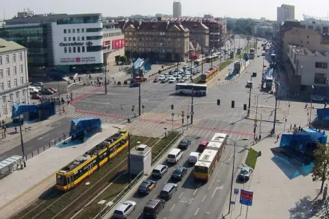 Żółty tramwaj na skrzyżowaniu z samochodami i autobusem.