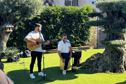 Dos músicos animan el jardín con rumbas para bailar. Uno toca la guitarra y canta, el otro canta y percute un cajón.