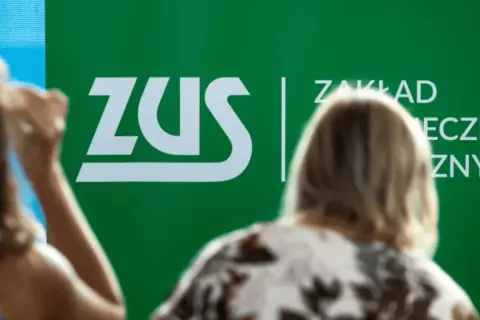 Ludzie przed zielonym banerem ZUS. Dyskusja o składce zdrowotnej 2026.