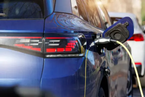 Niebieski samochód hybrydowy jest ładowany. To przyszłość motoryzacji, która łączy silnik spalinowy z elektrycznym.